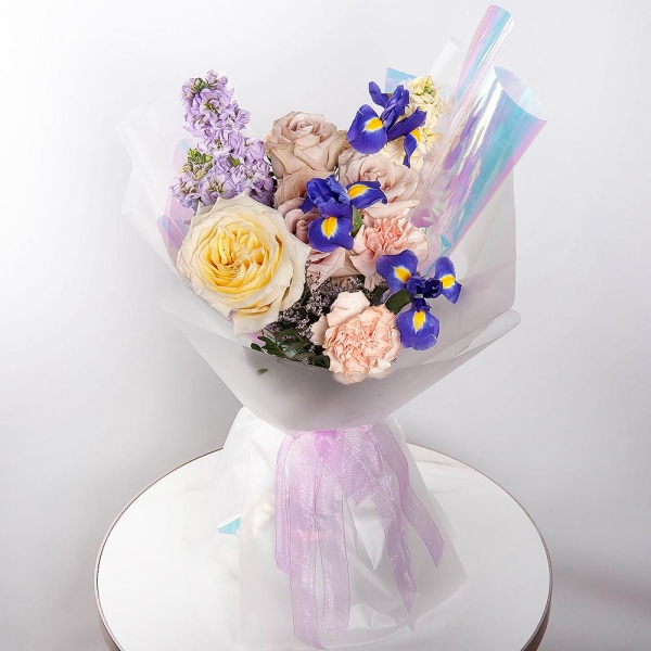 Irises - 3, Matthiola Lilac - 2, Rose Yellow 50 cm Ecuador (Mohana, Latina, Brighton) - 1, Cream Rose 50 cm Ecuador (Creme Caramel) - 3, Carnation white, cream - 5, White Matthiola - 1, Limonium (1 pc.), Pistachio, Wrapping Paper